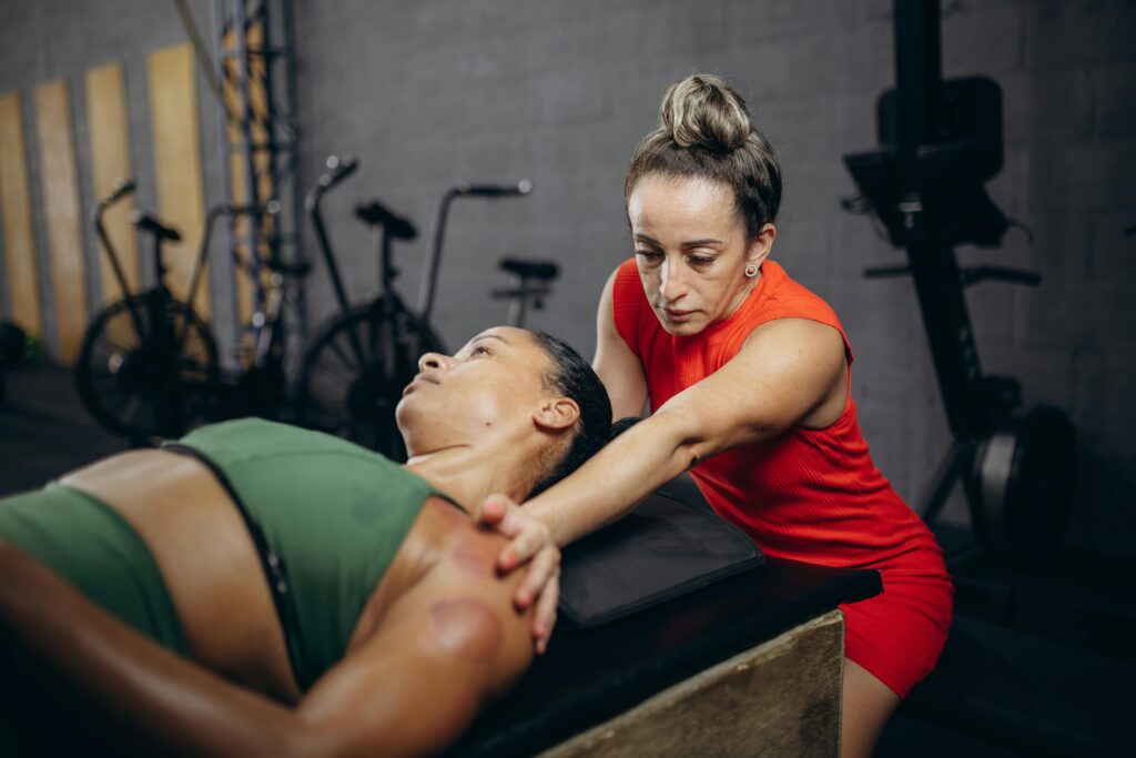 A therapist assists a woman with manual therapy to improve flexibility and mobility in a gym environment.